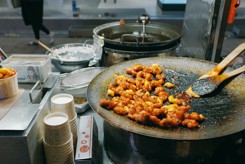 Korean stir-fried noodles cooking in a large wok over flames