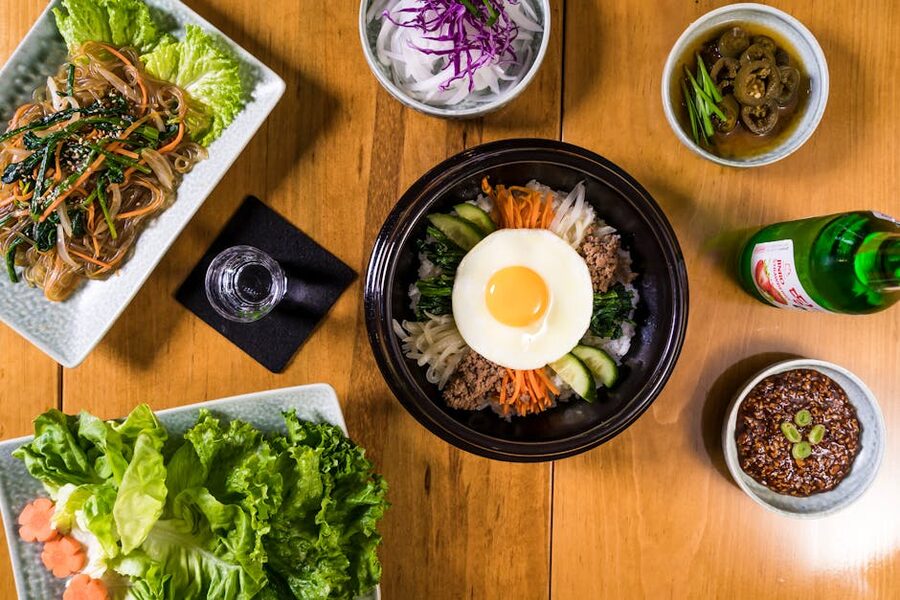 Overhead view of Korean dishes arranged with a bottle of soju