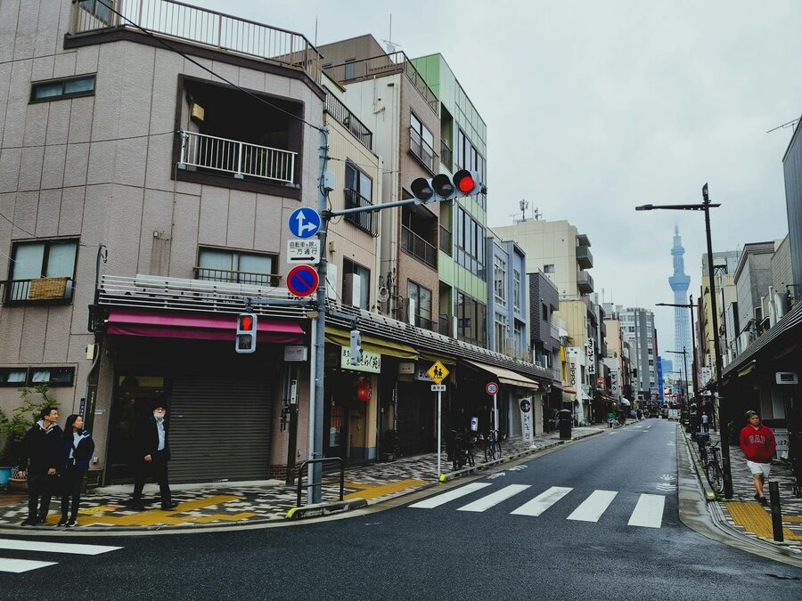 Busy Tokyo street with pedestrians and shops with Tokyo Skytree tower visible in the background