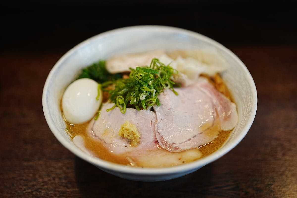 Close-up of a Japanese ramen bowl with a halved soft-boiled egg, sliced pork, and chopped green onions
