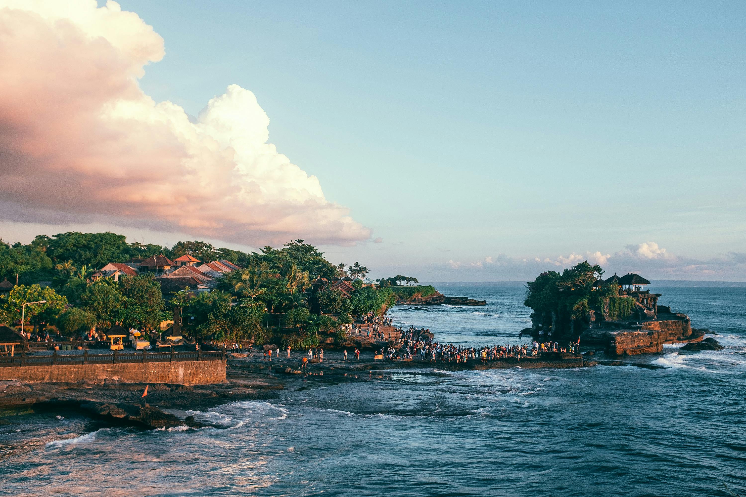 travellers walking on the rocky shoreline near Tanah Lot Temple
