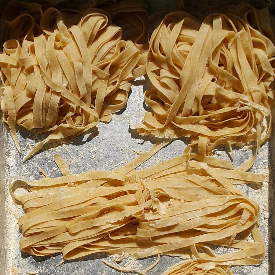 Fresh fettuccine pasta strands on a wooden board