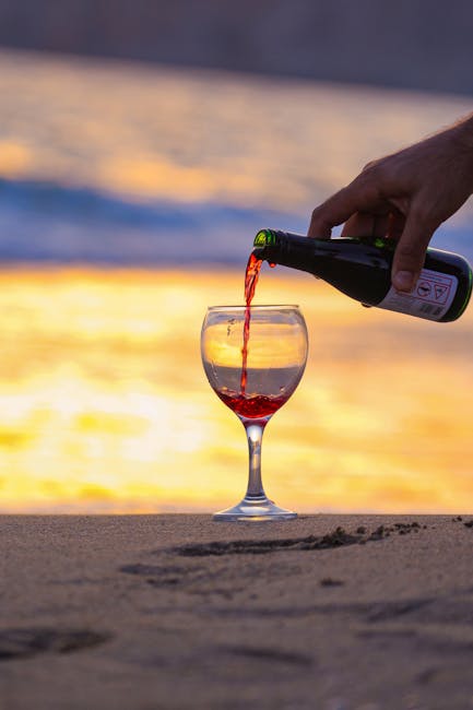 Hand pouring red wine glass sunset
