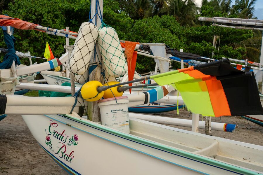 Traditional jukung fishing boats and speedboats lined up at Sanur harbour in Bali