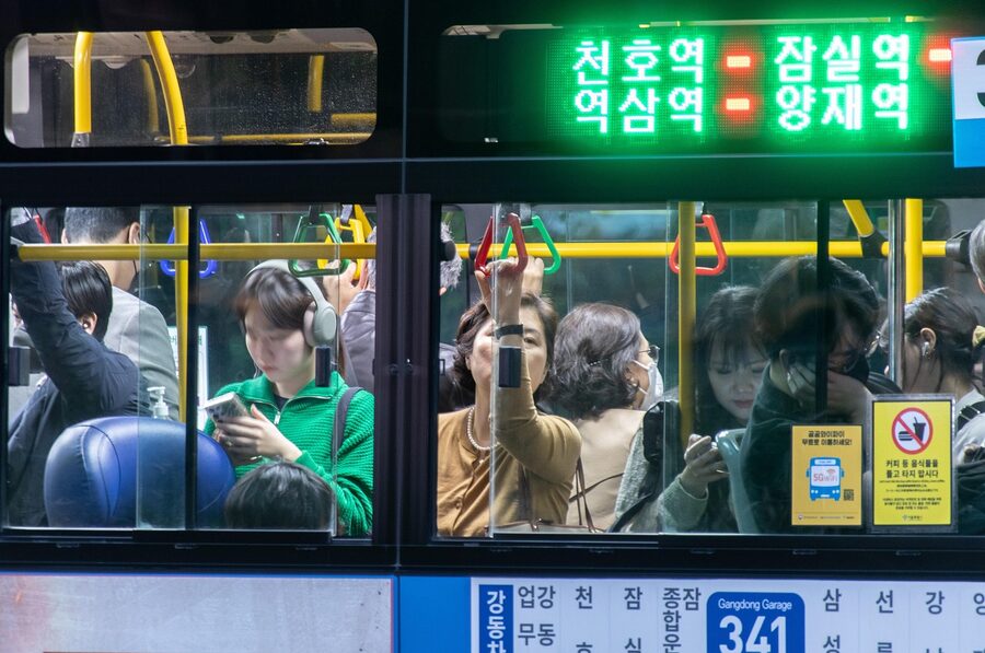Passengers standing inside a Seoul bus during a daytime ride