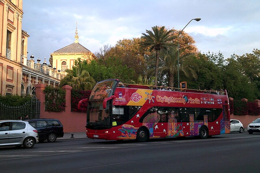 Seville City Sightseeing tour bus driving on a city street with the route board visible