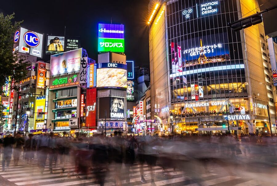 Shibuya Crossing at night in Tokyo with illuminated billboards and crowds