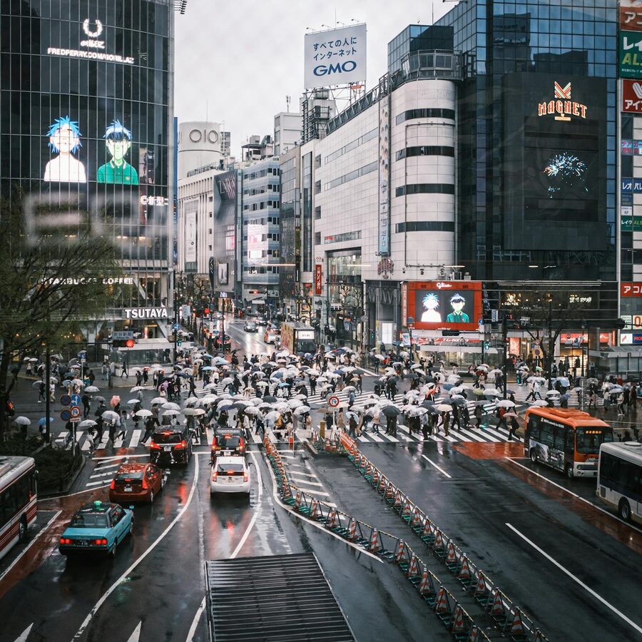 Crowded Shibuya Crossing with umbrellas and traffic