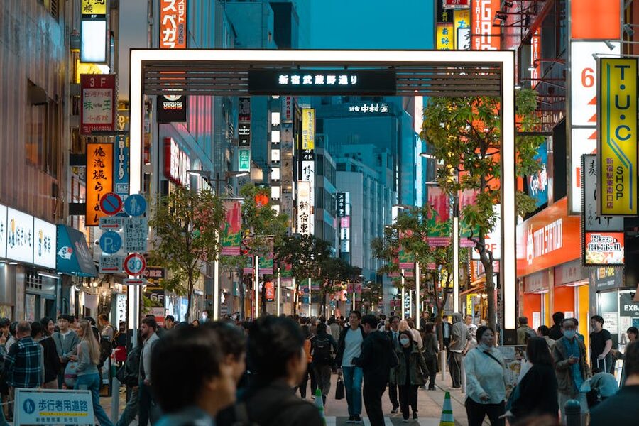 Shinjuku Tokyo night scene with crowds passing under neon signs