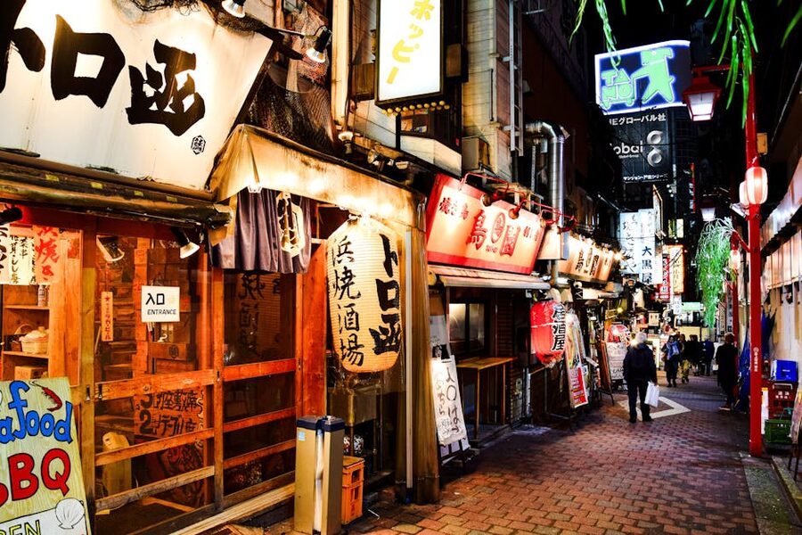 Illuminated Shinjuku alley lined with cafes and small bars at night