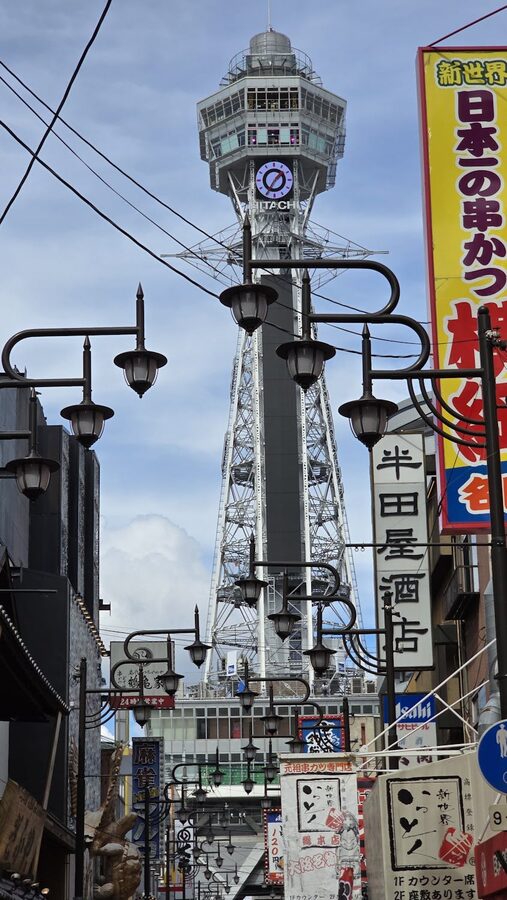 Colorful Shinsekai street with Tsutenkaku Tower and pedestrians in Osaka
