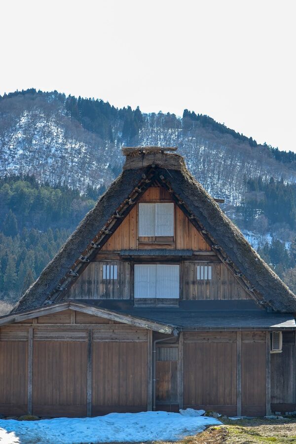 Classic Japanese Gassho-Zukuri house with snowy mountains in the background