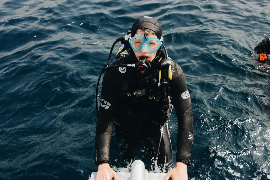 A snorkeler floating face-down over a tropical reef with light cutting through the water above