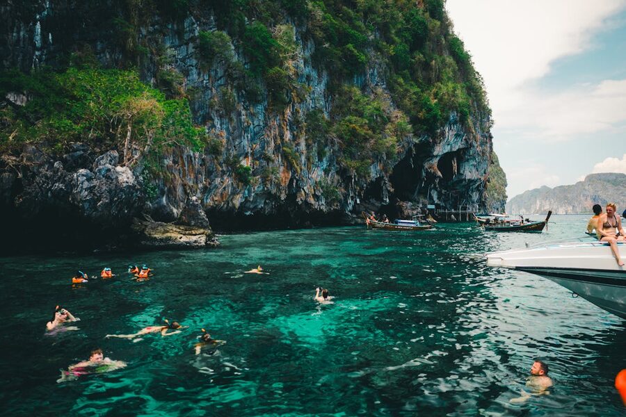 People swimming in turquoise water near limestone cliffs in Phuket Thailand