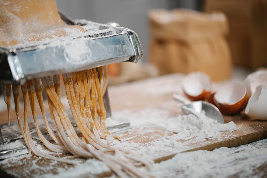 Spaghetti pressed through an iron cutter on a wooden bench