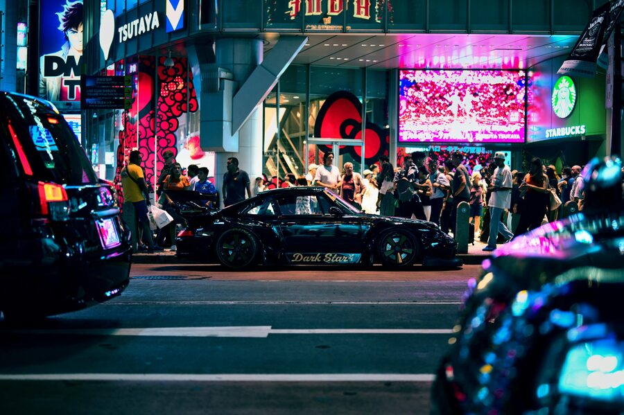 Sports car driving through neon-lit Tokyo streets at night