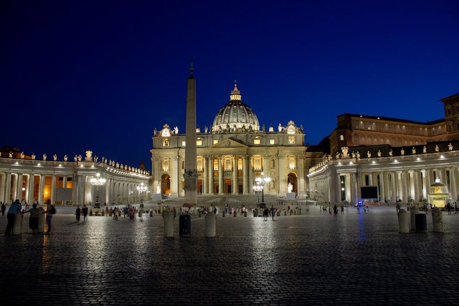 St Peter's Basilica lit up at night with the dome glowing above the square