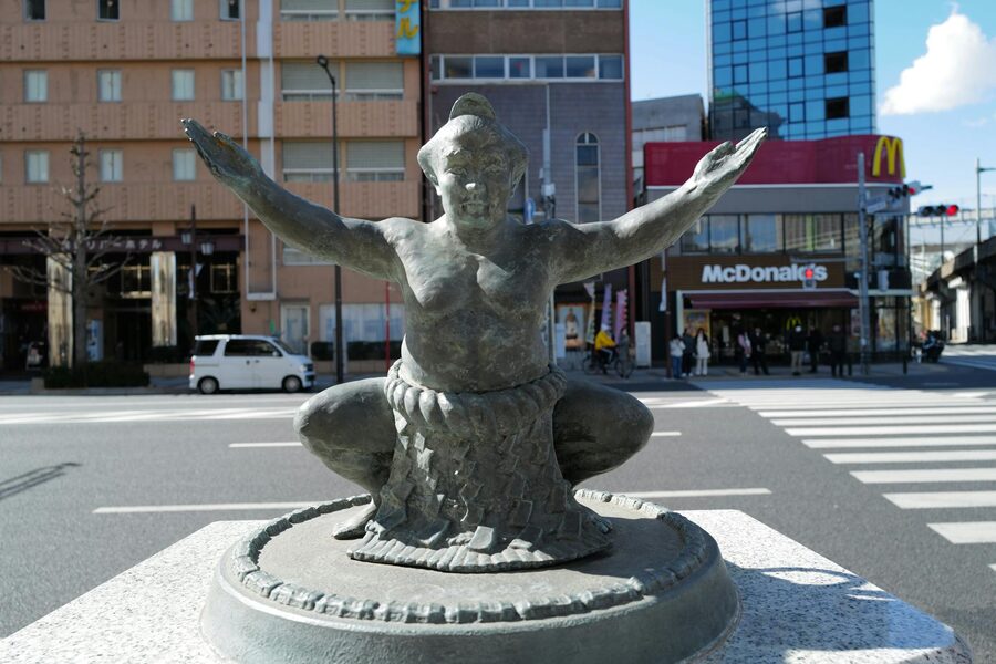Bronze sumo wrestler statue at urban intersection Tokyo