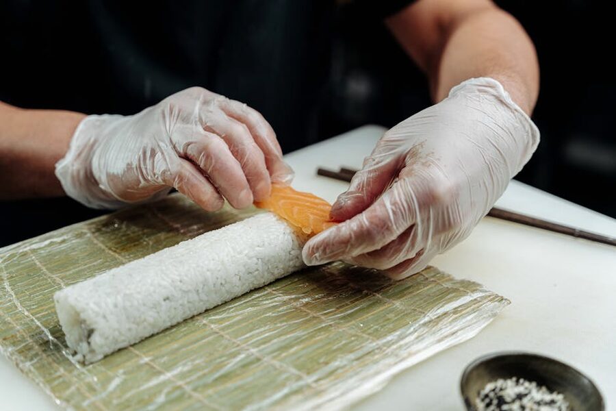 Placing salmon on sushi roll on bamboo mat
