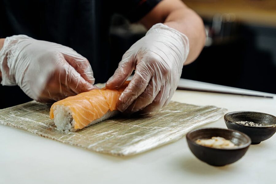 Chef rolling salmon sushi on bamboo mat
