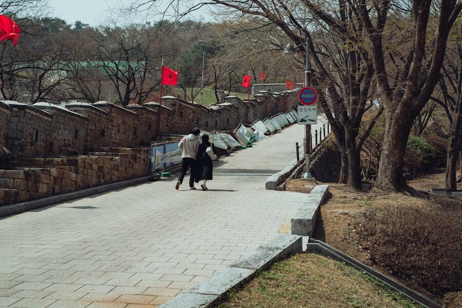 Couple walking the Hwaseong Fortress path in spring with red flags