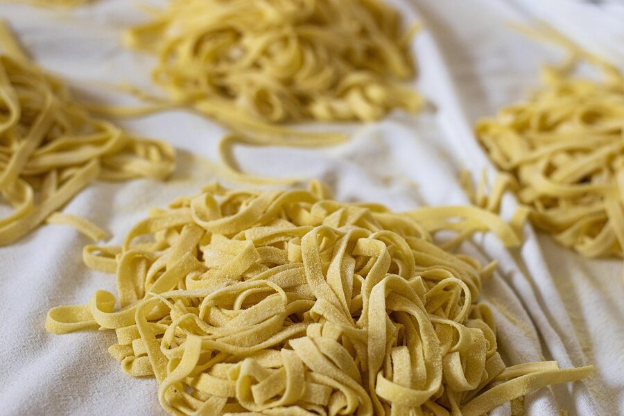 Fresh tagliatelle laid out on a wooden surface to dry