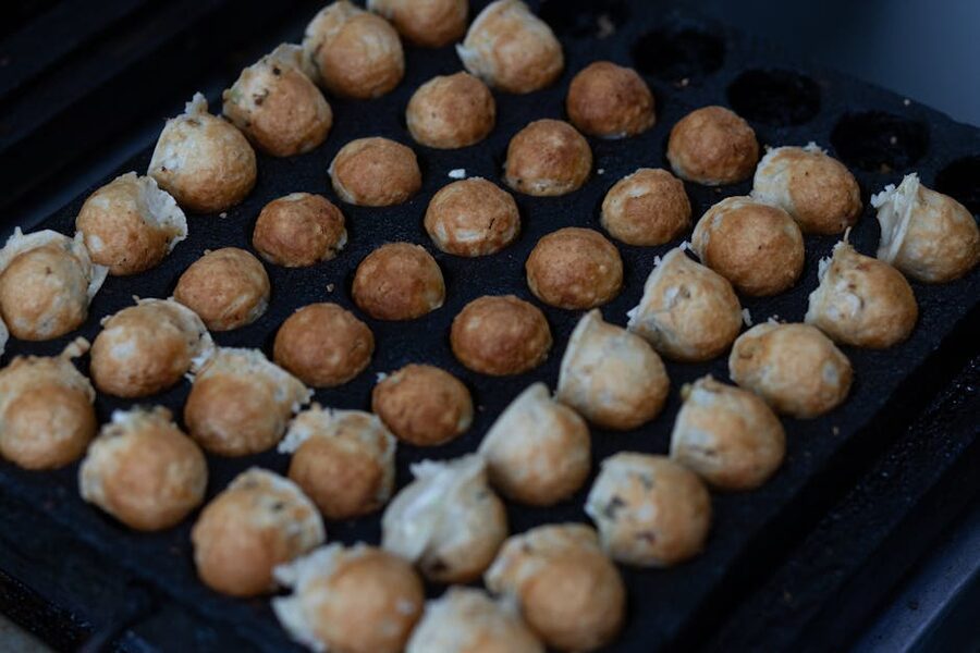 Takoyaki octopus balls cooking on a grill in Osaka