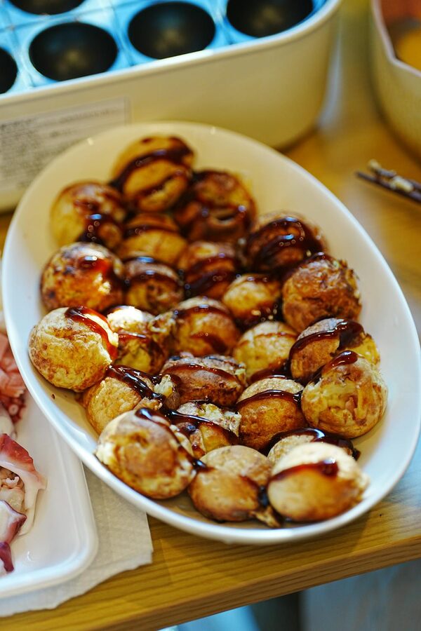Freshly made takoyaki balls drizzled with sauce served in a dish