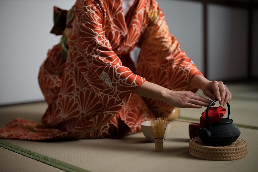 Close-up of a woman in kimono preparing for a Japanese tea ceremony indoors