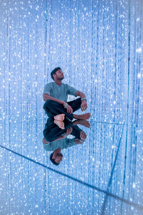 Person sitting barefoot in a digital art exhibit
