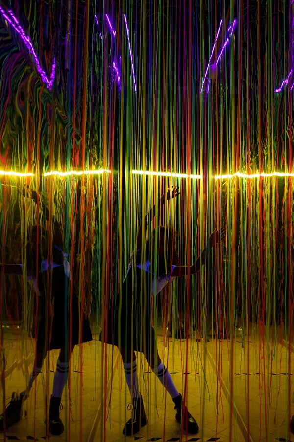 Person interacting with neon ropes with colorful reflection
