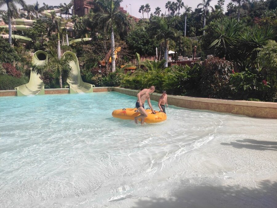 Blue water slide curving down with Thai pavilion details at Siam Park