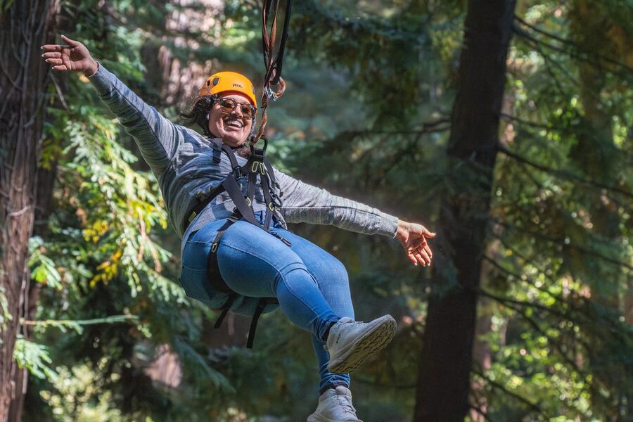 Happy woman ziplining through forest enjoying the adventure