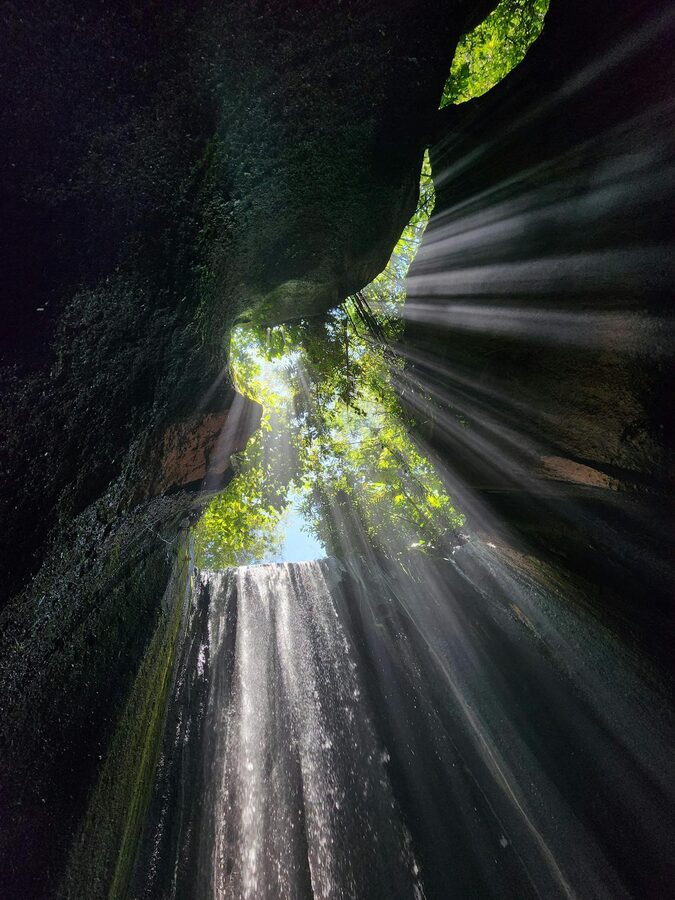 Tibumana waterfall flowing down a jungle cliff into a green plunge pool in central Bali