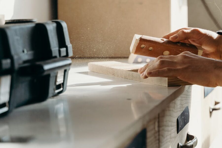 Close-up of hands sanding a piece of wood with careful technique