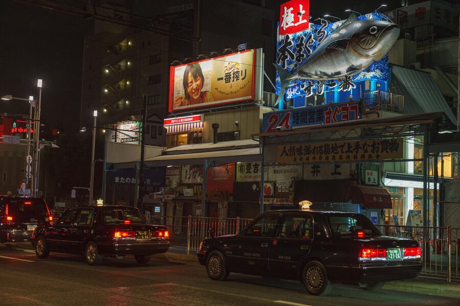Illuminated Tokyo street with taxis and bright neon billboards at night