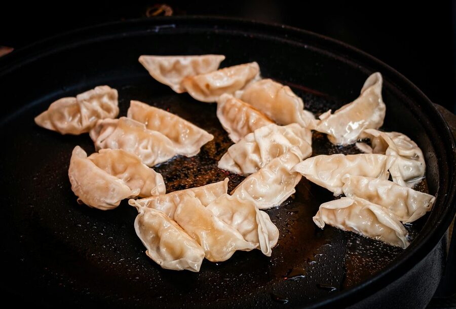 Pan-fried gyoza dumplings sizzling on a hot skillet