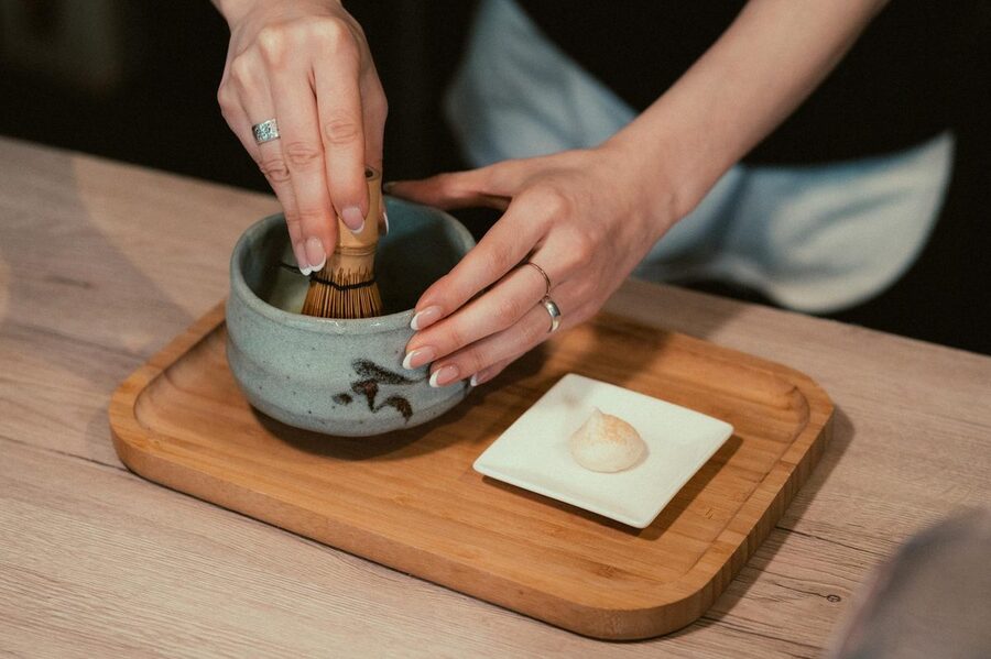 Hands preparing matcha tea with bamboo take