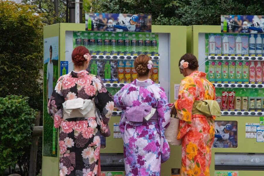 Women in colorful kimonos at vending machines in Japan