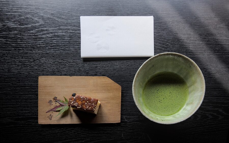 Matcha green tea in a bowl with traditional Japanese cakes