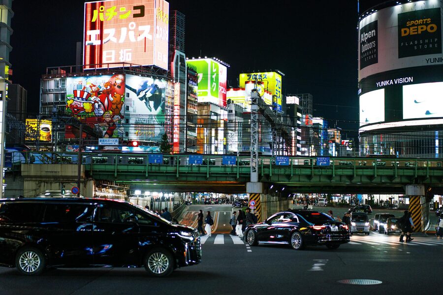 Shinjuku Tokyo street scene at night with bright neon lights and traffic