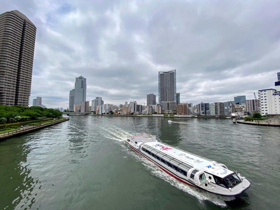 Tokyo skyline with ferry boat on the river during daytime