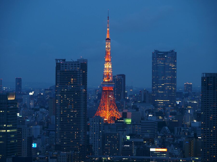 Brightly lit Tokyo Tower amid modern Tokyo buildings at night