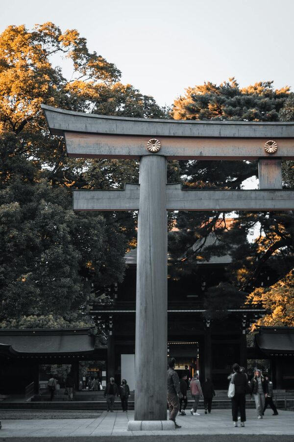 Traditional torii gate surrounded by lush green trees at a Japanese temple