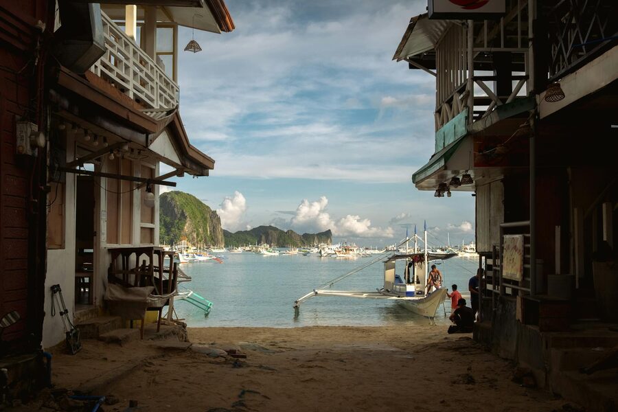 View of boats and cliffs from a coastal street in El Nido town