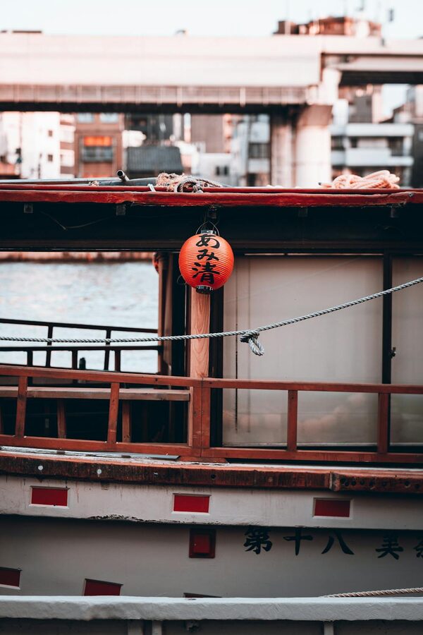 A traditional Japanese boat moored on the Sumida River with city buildings in the background