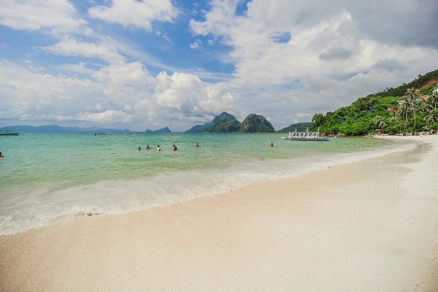Tropical beach with turquoise water and swimmers in El Nido