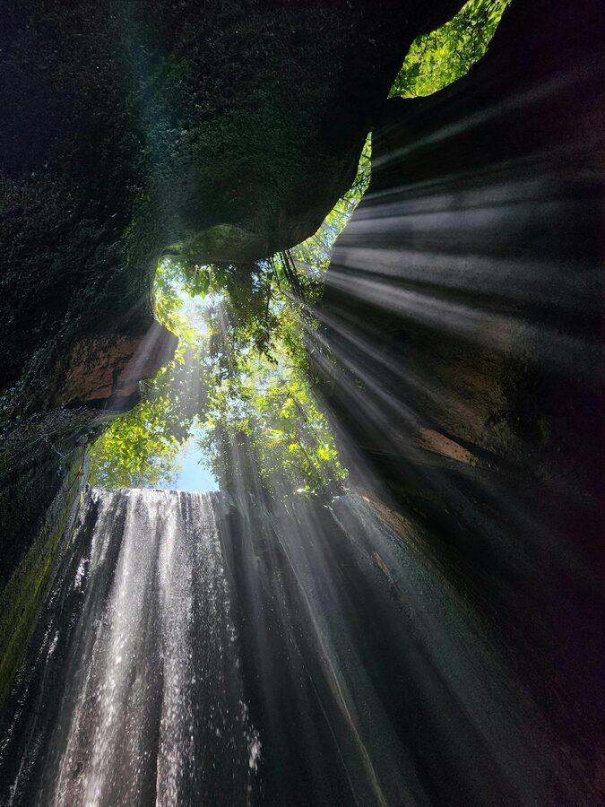 Close-up view inside Tukad Cepung cave with moss walls and flowing water