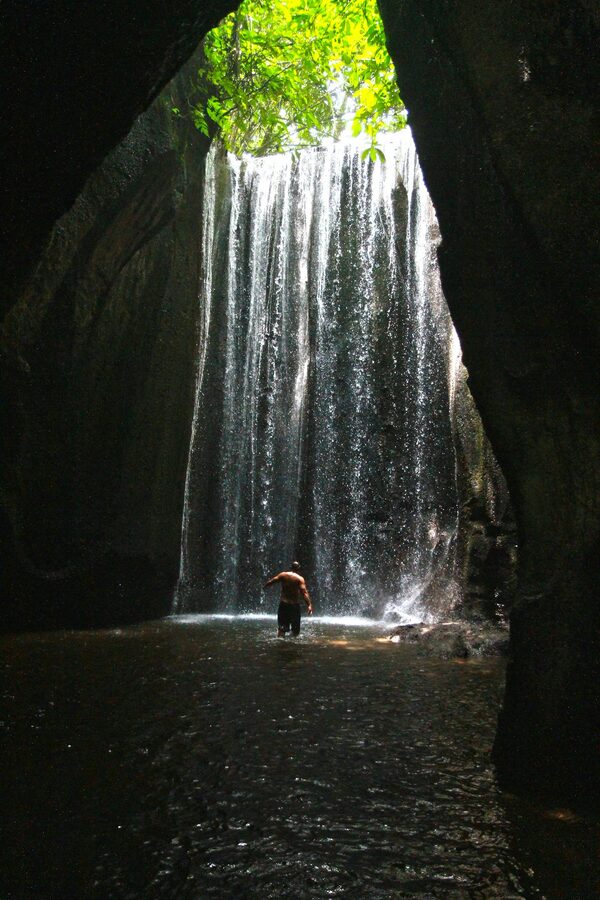 A shaft of morning sunlight piercing through the cave ceiling at Tukad Cepung waterfall in Bali