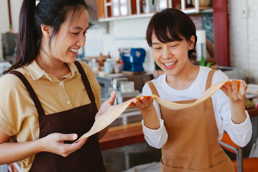 Two students laughing while stretching pasta dough at a Florence cooking class